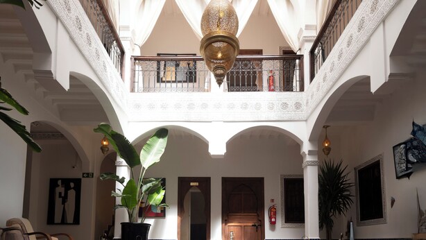 Ein luxuriöses Interieur mit einem zentralen Pool, verzierten Bögen und einer hohen Decke mit Oberlicht.