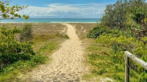 A sandy path leading to a beach with a clear sky and some clouds. - Beachfront Apartment with Hot Tub & Pool (Bilinga)