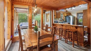 Un intérieur en bois comprenant un coin repas, une cuisine et un canapé à l’arrière-plan.