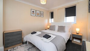 Habitació d'hotel ben ordenada, amb un llit, taules de nit, un armari i obra d'art a la paret.