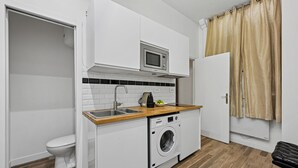 A compact kitchen with a built-in microwave, a washing machine, and a sink.