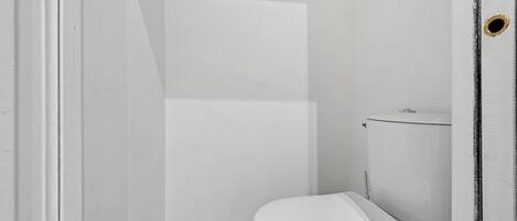 Un baño pequeño y blanco con inodoro y cabina de ducha.