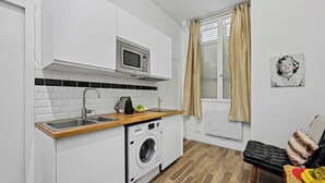 A compact kitchen with a microwave, sink, and washing machine.