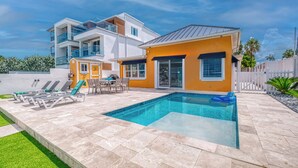 Ein modernes, zweistöckiges Haus mit Swimmingpool, Außenbereich und umzäunter Rückseite.
