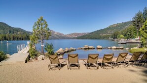A lakeside view with a dock, chairs, and a clear sky.