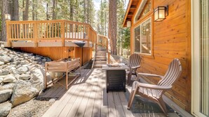 A wooden deck with a table and chairs, a small heater, and a stone wall.