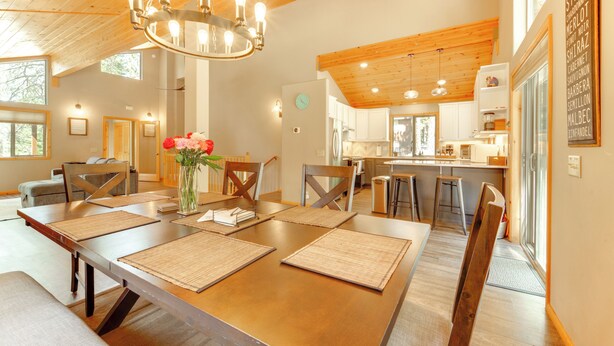 A spacious dining area with a long wooden table, multiple chairs, and a chandelier.