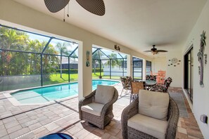 A covered patio with a pool, wicker furniture, and a dining area with chairs and a table. - Family Retreat w/ Backyard Oasis in Cape Coral! (Cape Coral)