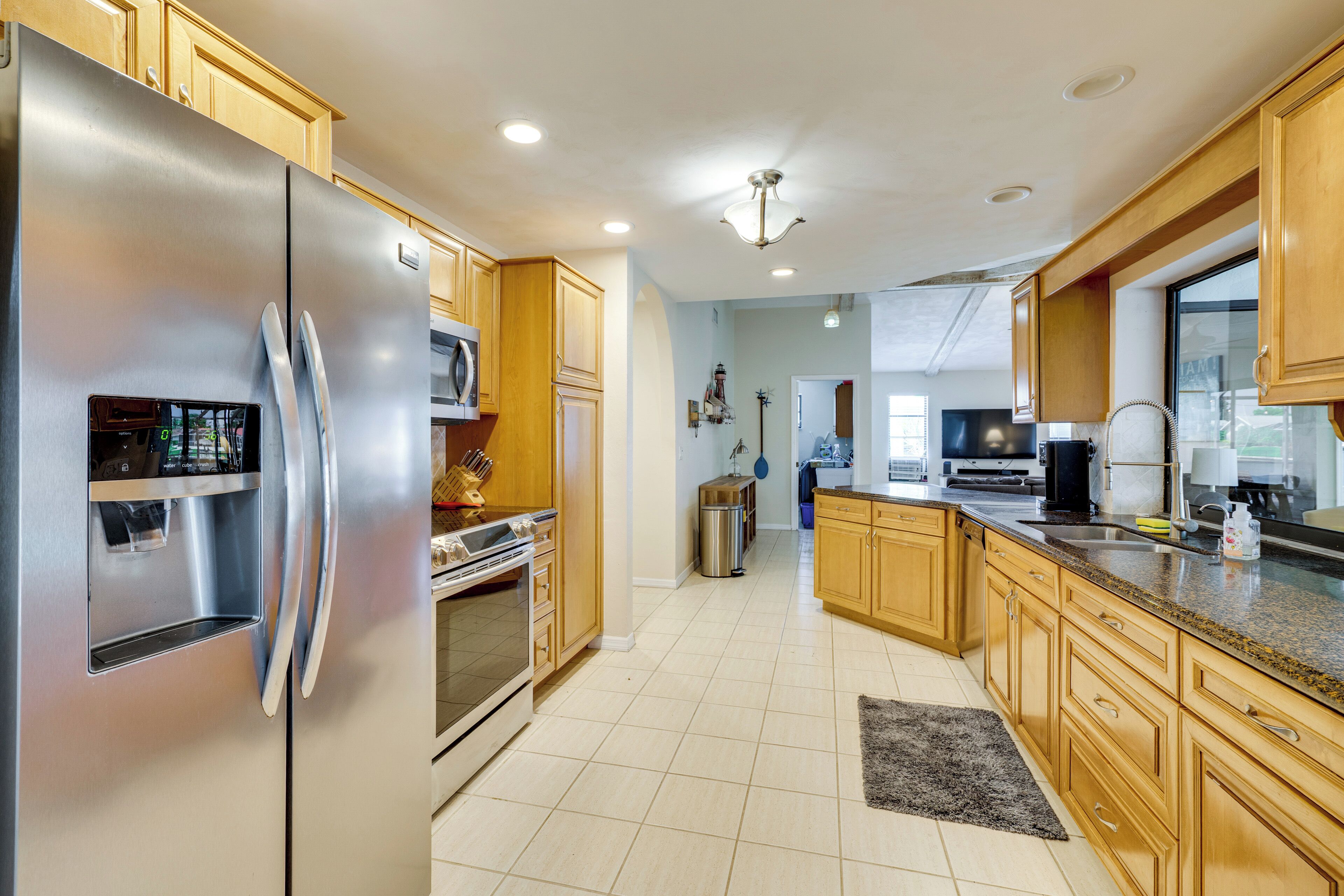 A modern kitchen with stainless steel appliances, wooden cabinets, and a tiled floor.