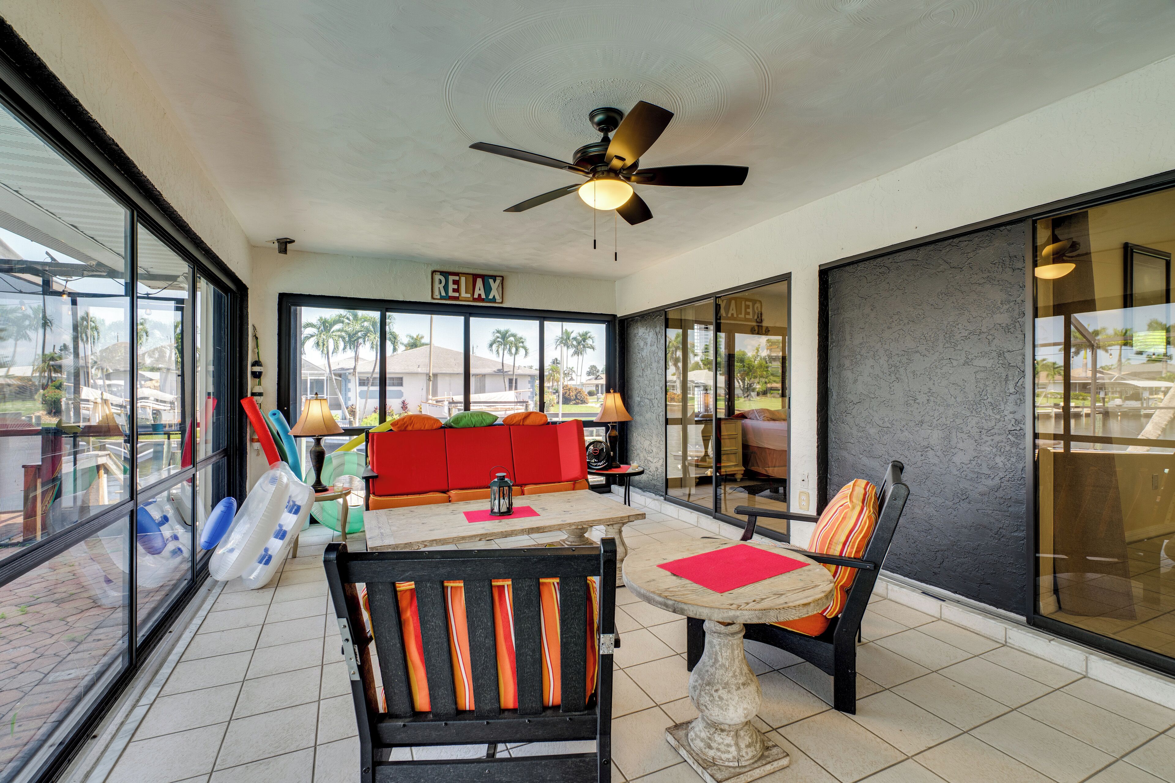 A spacious patio area with a ceiling fan, a red sofa, and a table with chairs.