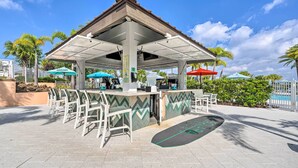 Un espace extérieur abrité, aménagé avec un bar, des chaises et des parasols.