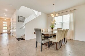 A dining area with a wooden table, six chairs, and a chandelier. - Home Near Theme Parks in Kissimmee: Family Perks! (Kissimmee)