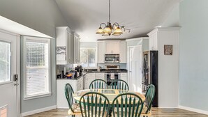 A kitchen with white cabinets, a dining table with chairs, and a chandelier. - Family Home w/ Fenced Yard Between Provo & Slc! (Herriman)