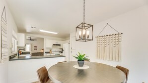 Un comedor con una mesa redonda, sillas de cuero marrón, una lámpara colgante y una planta sobre la mesa.