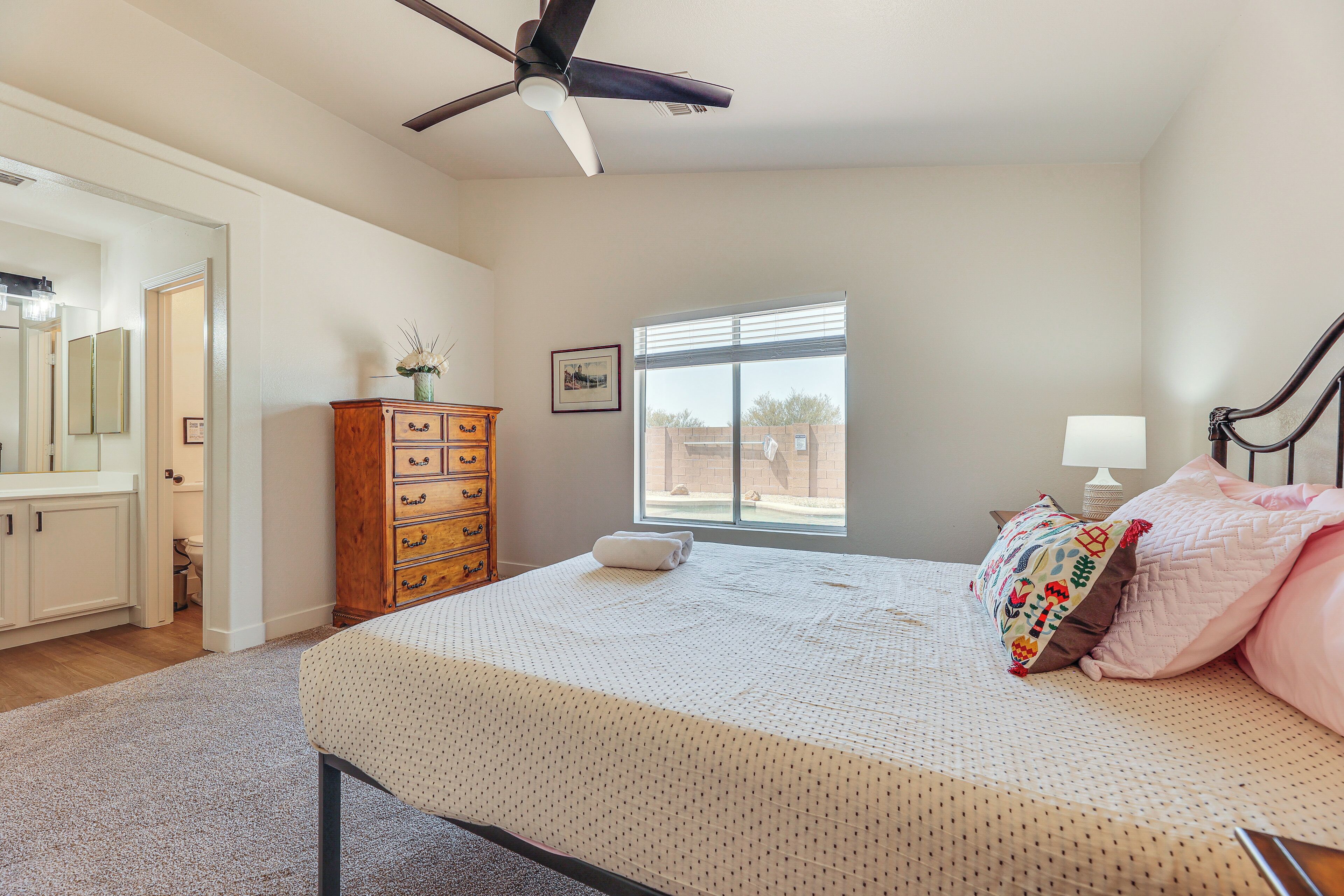 A bedroom with a bed, dresser, window, and ceiling fan.