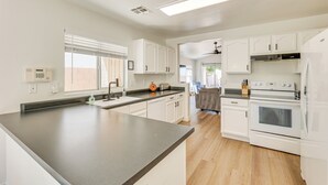 Una cocina moderna con armarios blancos, una encimera gris y un horno empotrado.