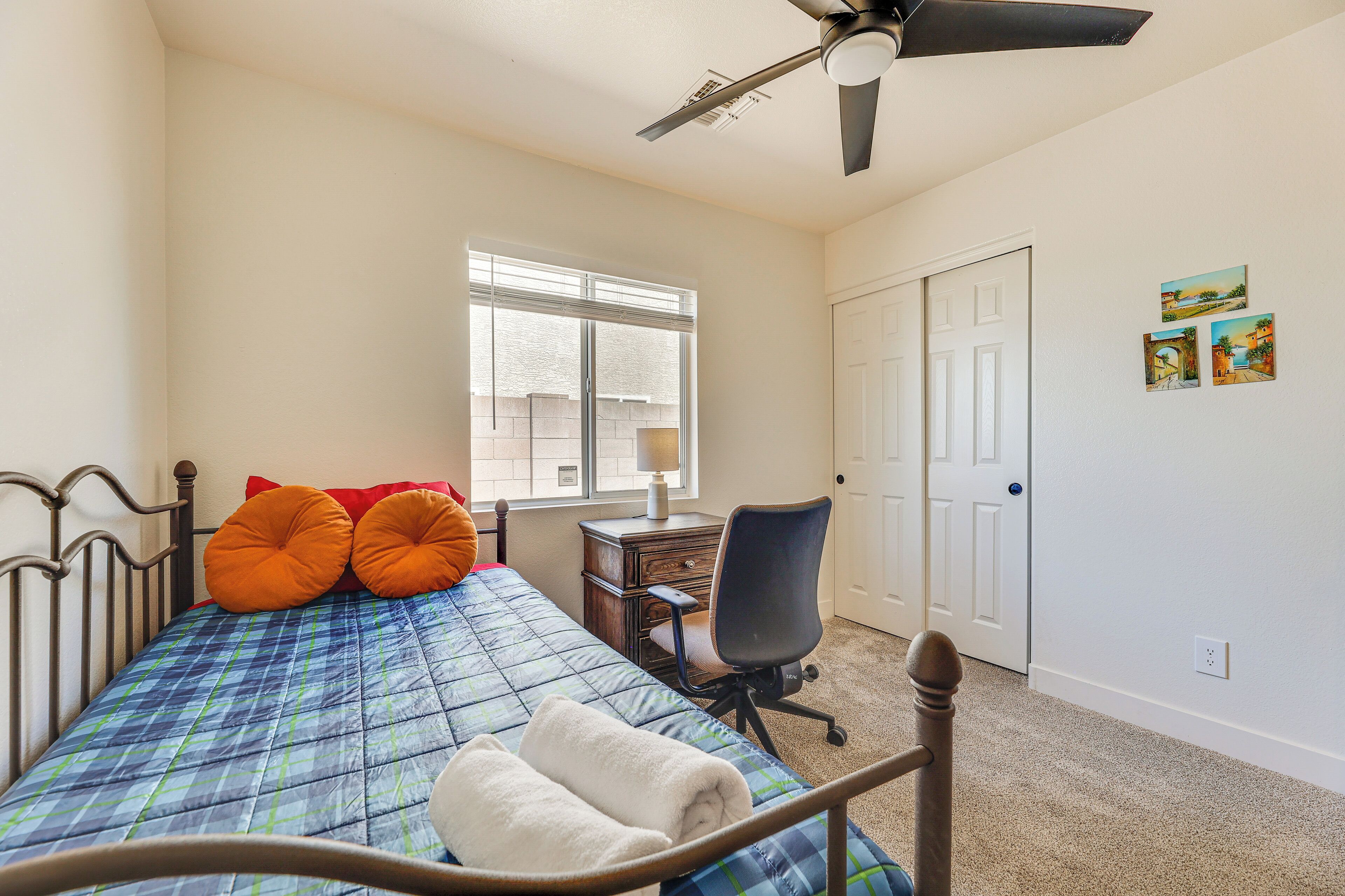 Ein Schlafzimmer mit Bett, Schreibtisch, Stuhl, Fenster und Tür.