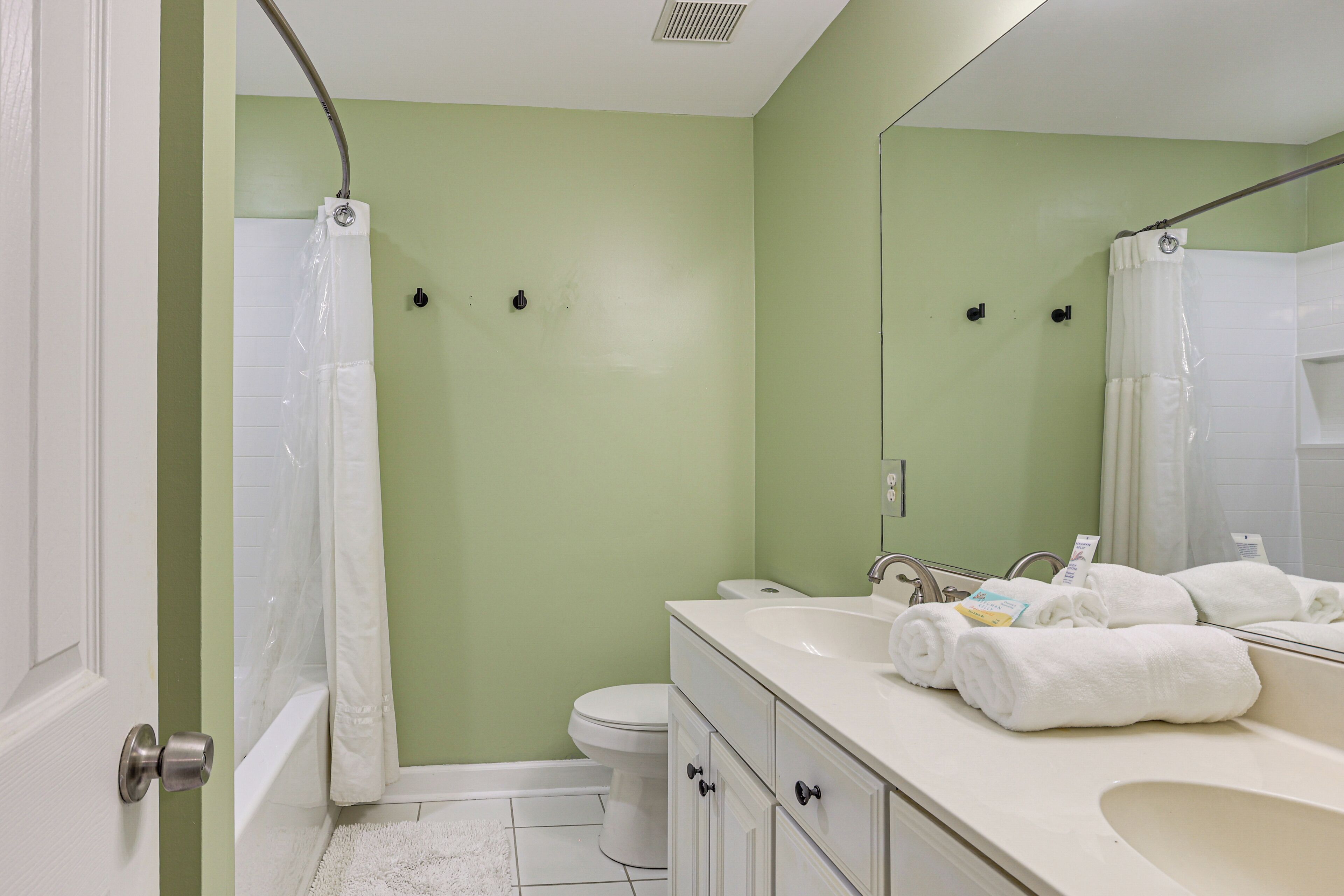 A bathroom with a shower, toilet, sink, and towels.