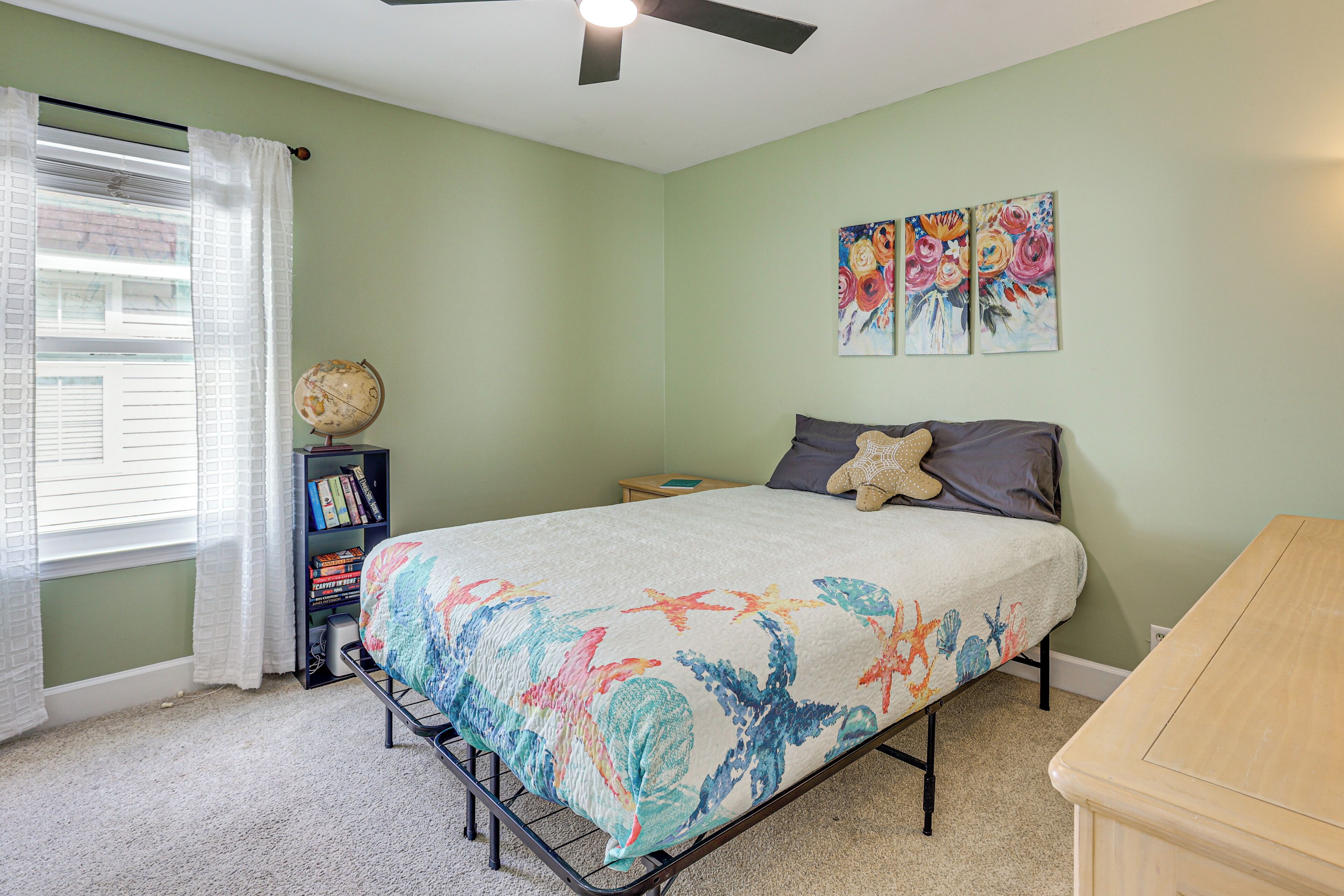 A bedroom with a bed, a ceiling fan, a globe, and a bookshelf.