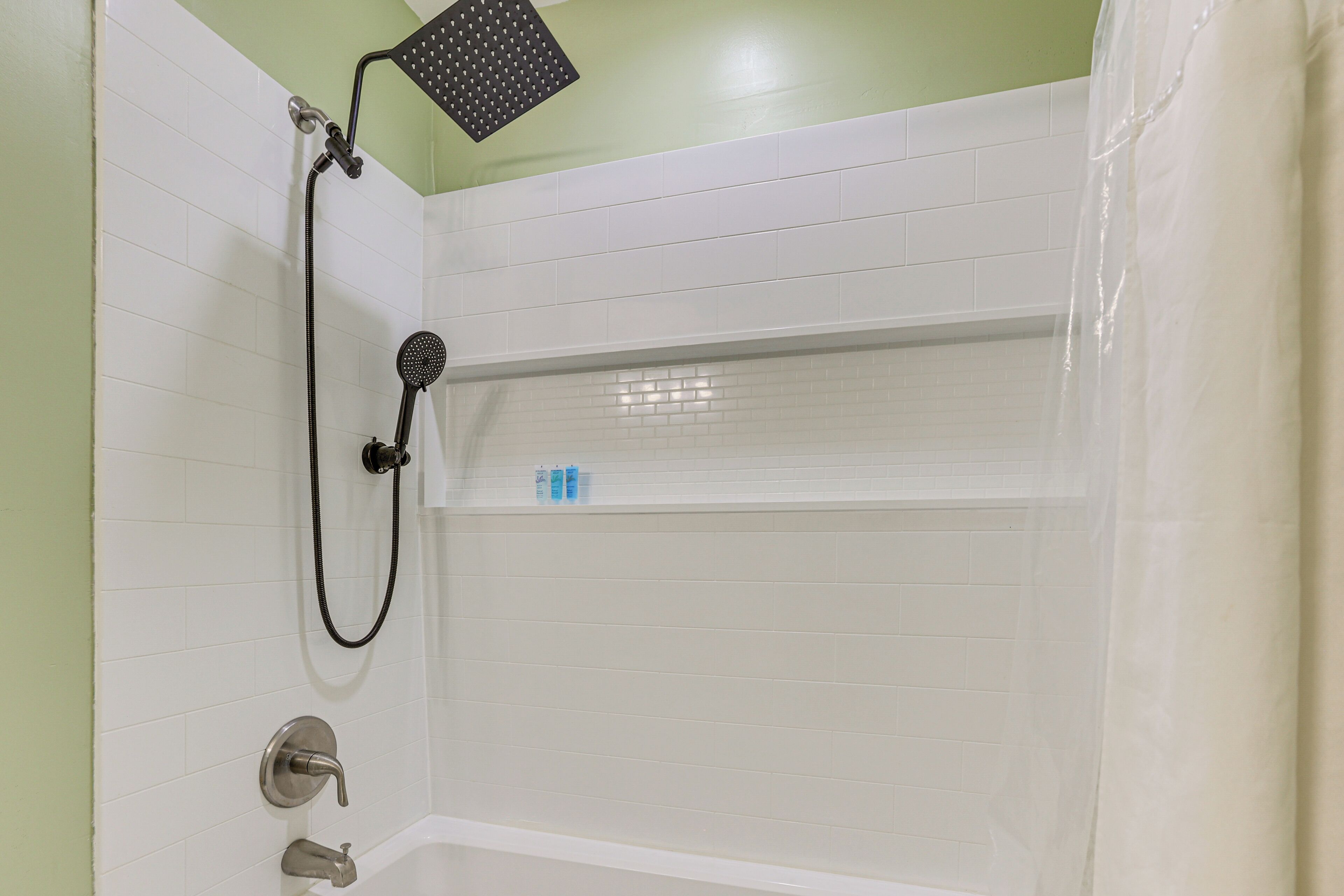 Un espacio con ducha, grifo de pared y cabezal de ducha manual.