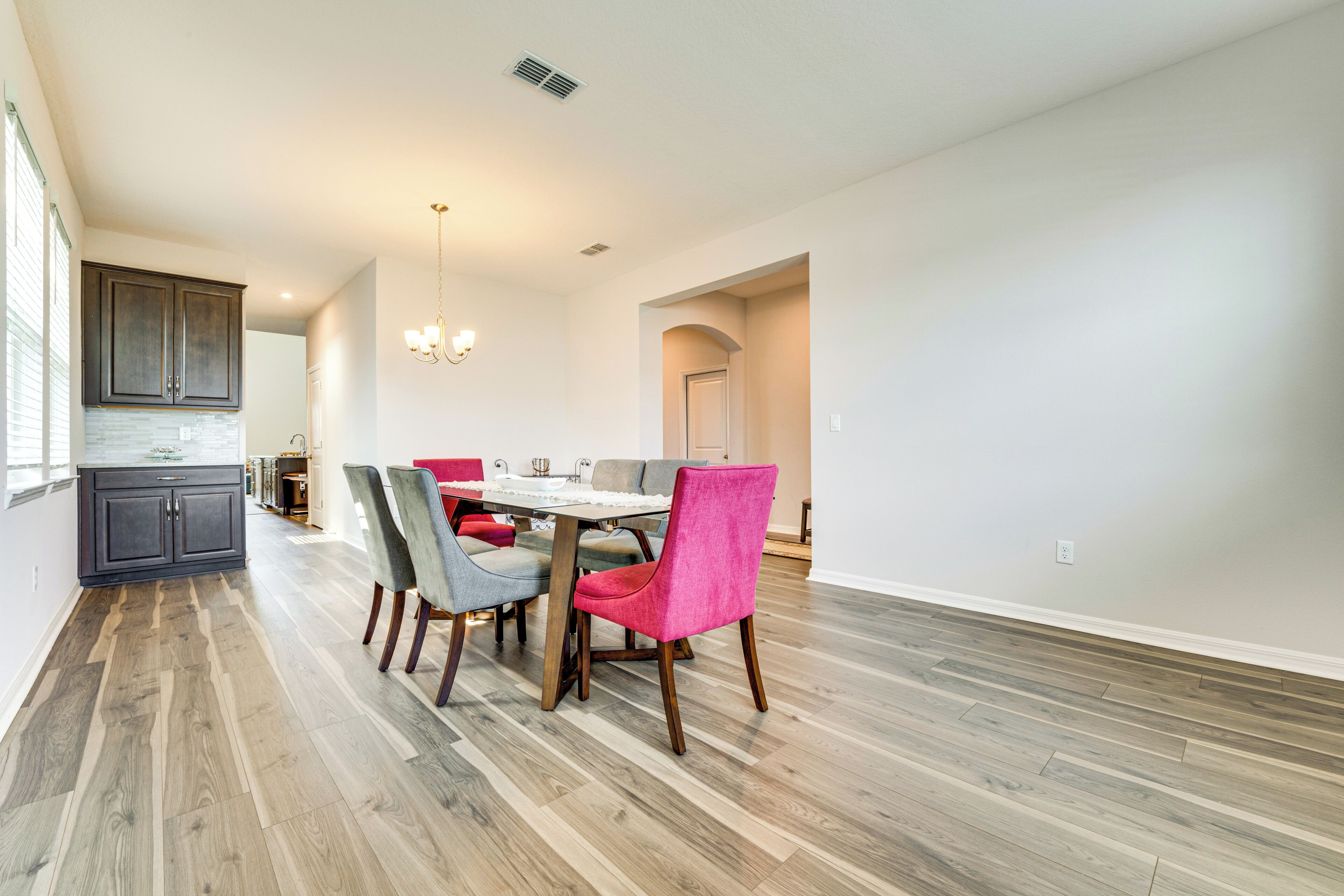 A spacious dining area with a wooden floor, a dining table, and chairs.