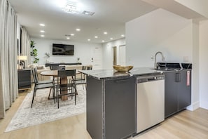 A modern kitchen with a central island, built-in dishwasher, and a dining area with a table and chairs.
