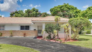 A single-story house with a tiled roof, a front porch, and a well-maintained lawn. - Walk to City Center: Modern Coral Springs Getaway (Coral Springs)