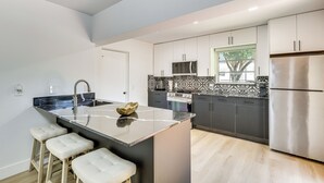 A modern kitchen with a central island, stainless steel appliances, and a patterned backsplash. - Walk to City Center: Modern Coral Springs Getaway (Coral Springs)