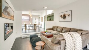 Una sala de estar moderna con un sofá de cuero marrón, una mesa de centro y un comedor al fondo.