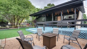 Un espacio al aire libre cubierto con sillas y una mesa, una terraza de madera y una casa con porche.
