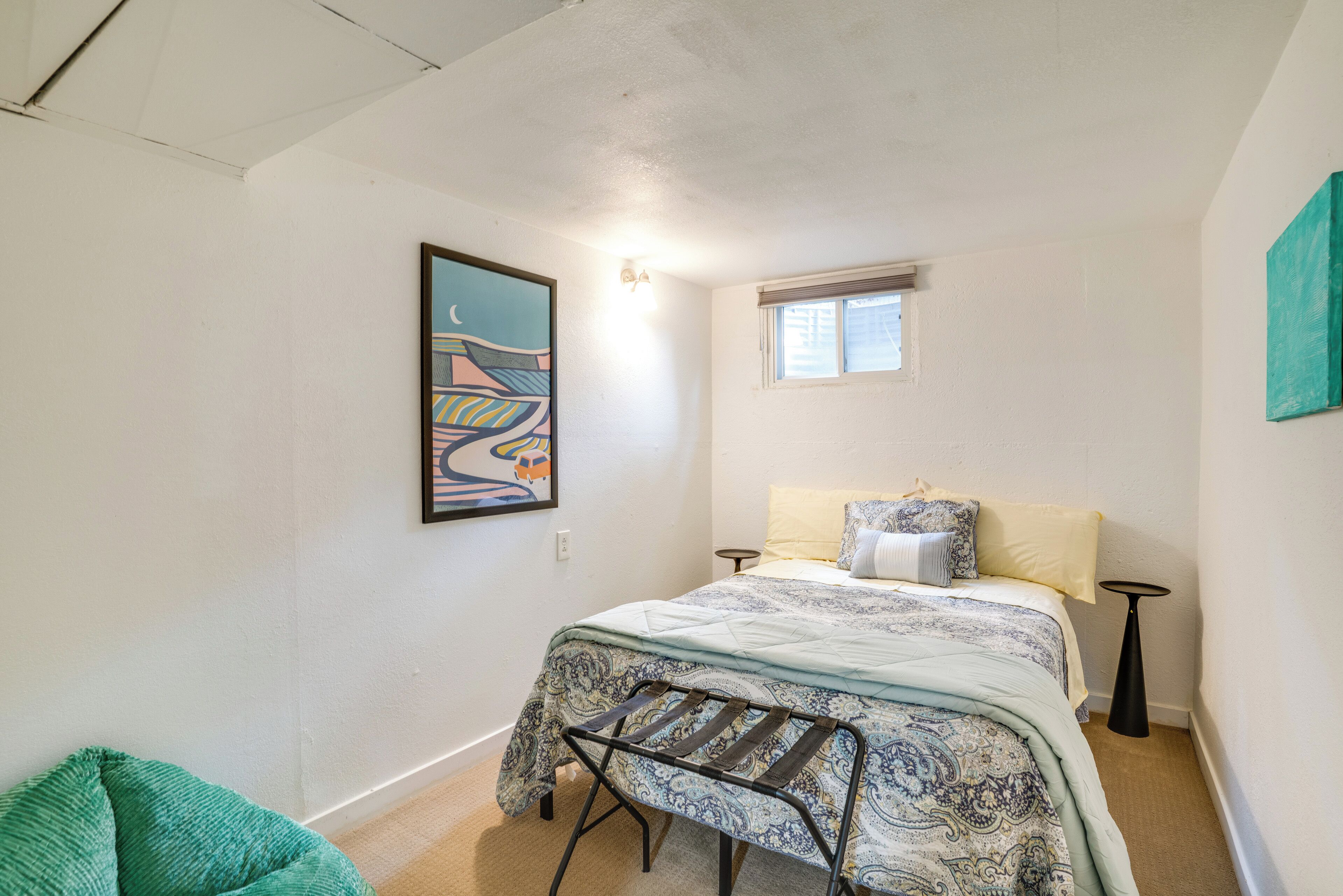 Ein Schlafzimmer mit einem Bett, einem Fenster, einer Wandleuchte und einem Bild.