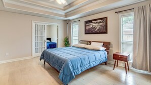 A bedroom with a bed, a nightstand, a ceiling fan, a window with curtains, and a door leading to another room. - 8 Mi to Lake Palestine: Peaceful Family Retreat (Flint)