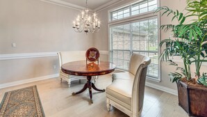 A dining area with a round table, two chairs, a chandelier, and a large window with blinds. - 8 Mi to Lake Palestine: Peaceful Family Retreat (Flint)
