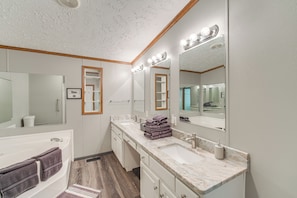 Une salle de bain moderne avec une baignoire, deux lavabos et un grand miroir avec éclairage intégré.
