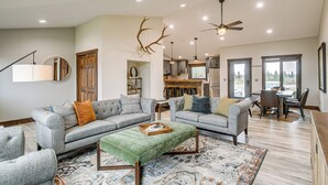 A spacious living room with grey sofas, a green ottoman, and a large rug. There is a ceiling fan and recessed lighting. - Pinedale Getaway Near Hiking, Skiing & Lakes! (Pinedale)