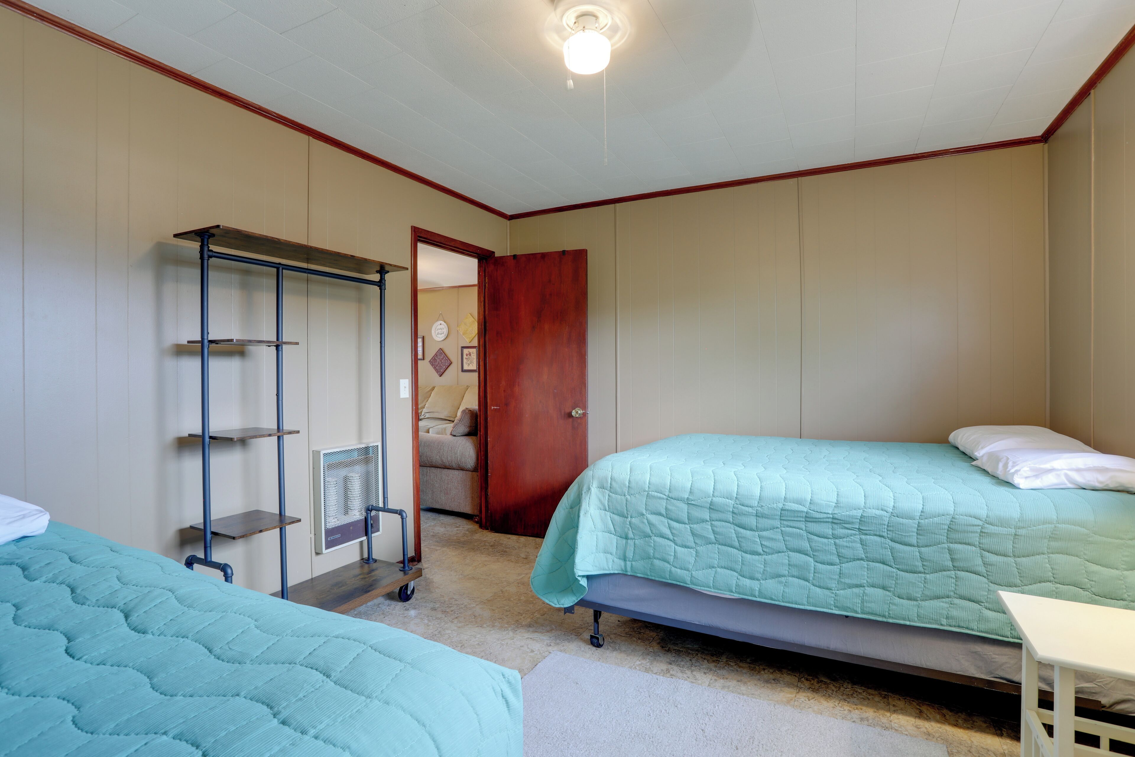 A bedroom with two beds, a wooden door, and a metal shelf unit.