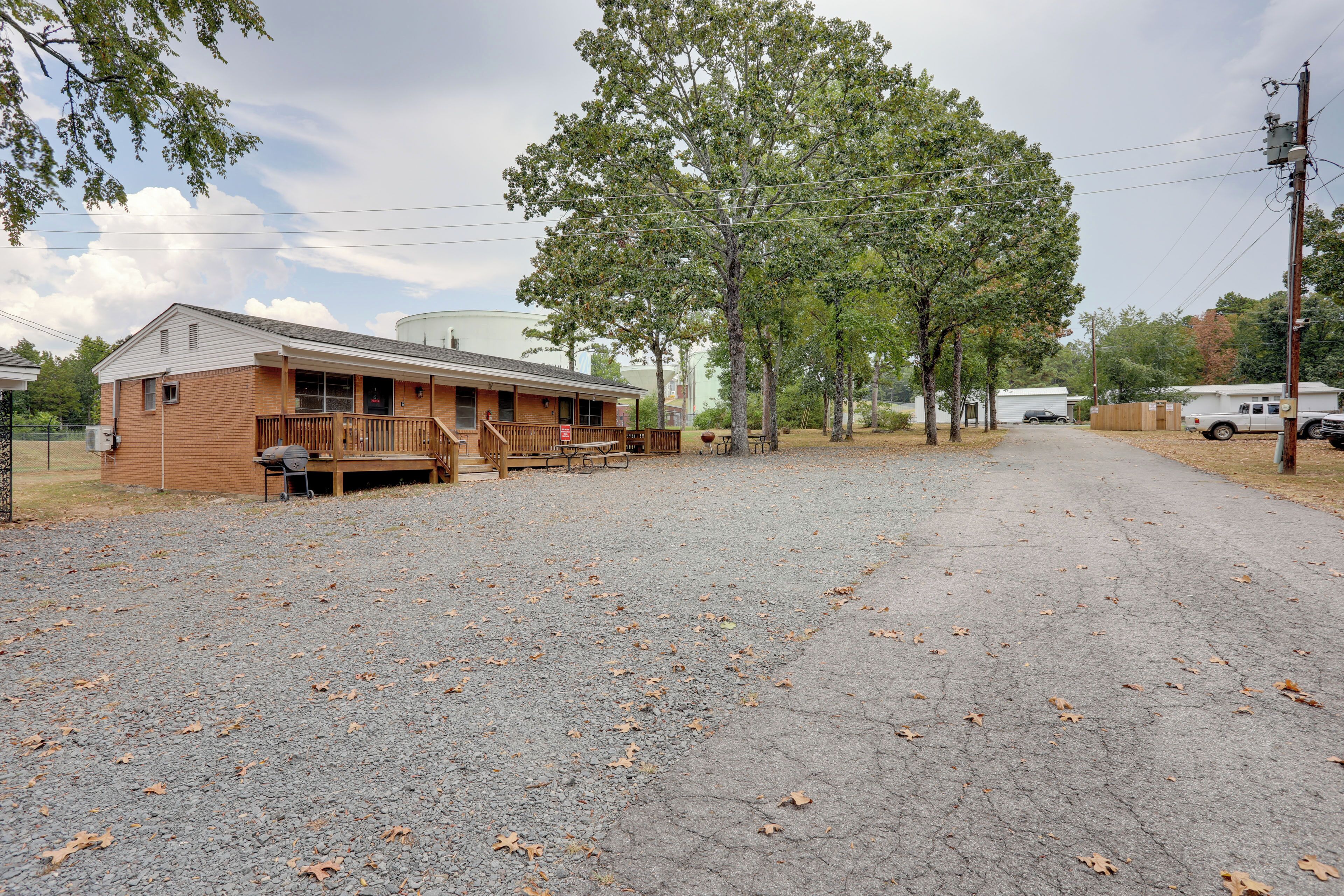 A rustic cabin with a porch, picnic table, and a gravel driveway.