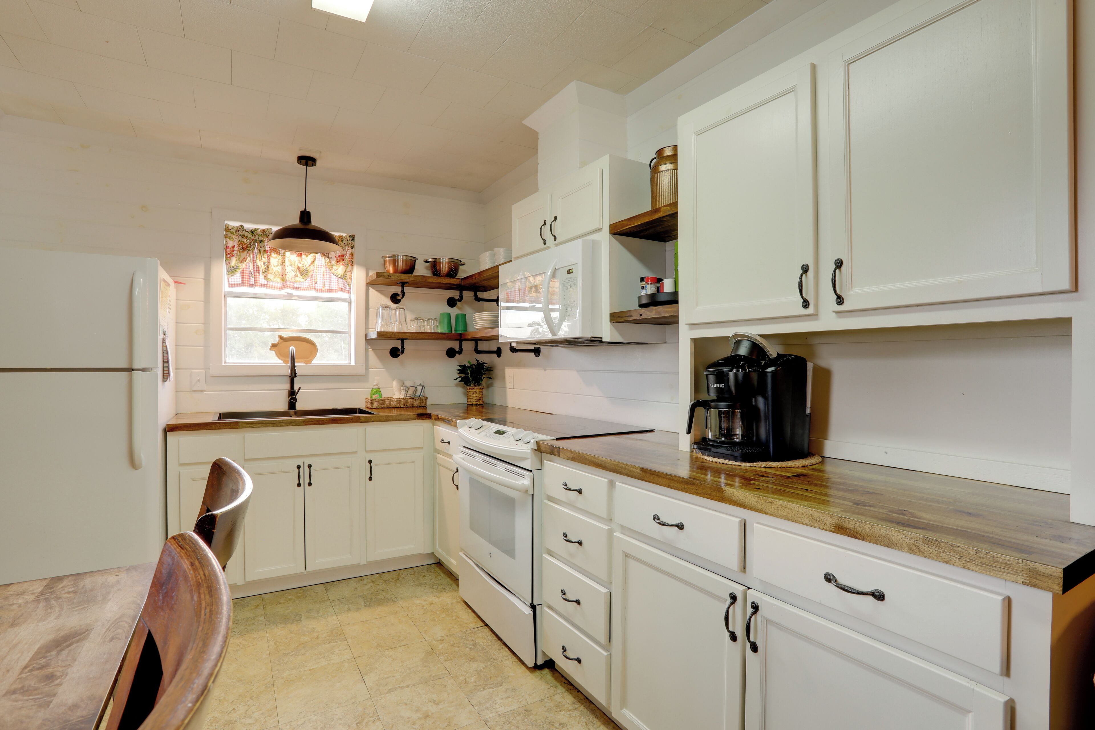A kitchen with white cabinets, a wooden countertop, a stove, and a sink.