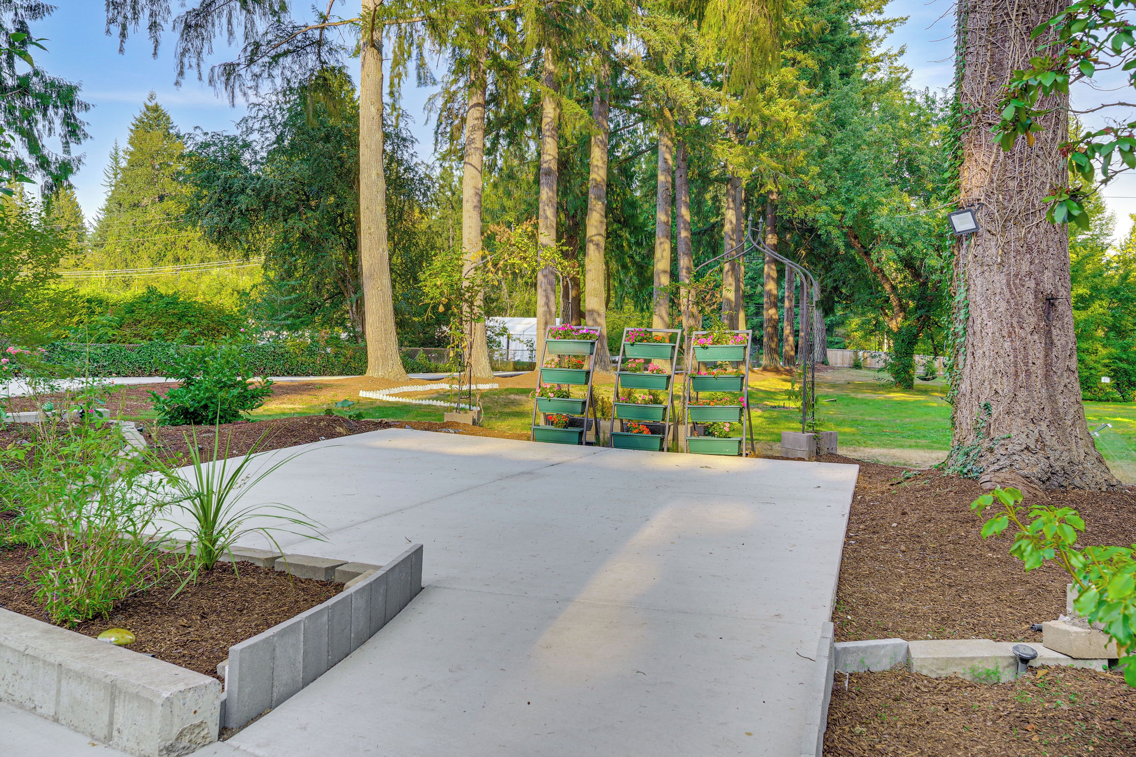 A concrete pathway leading to a seating area with green planters.