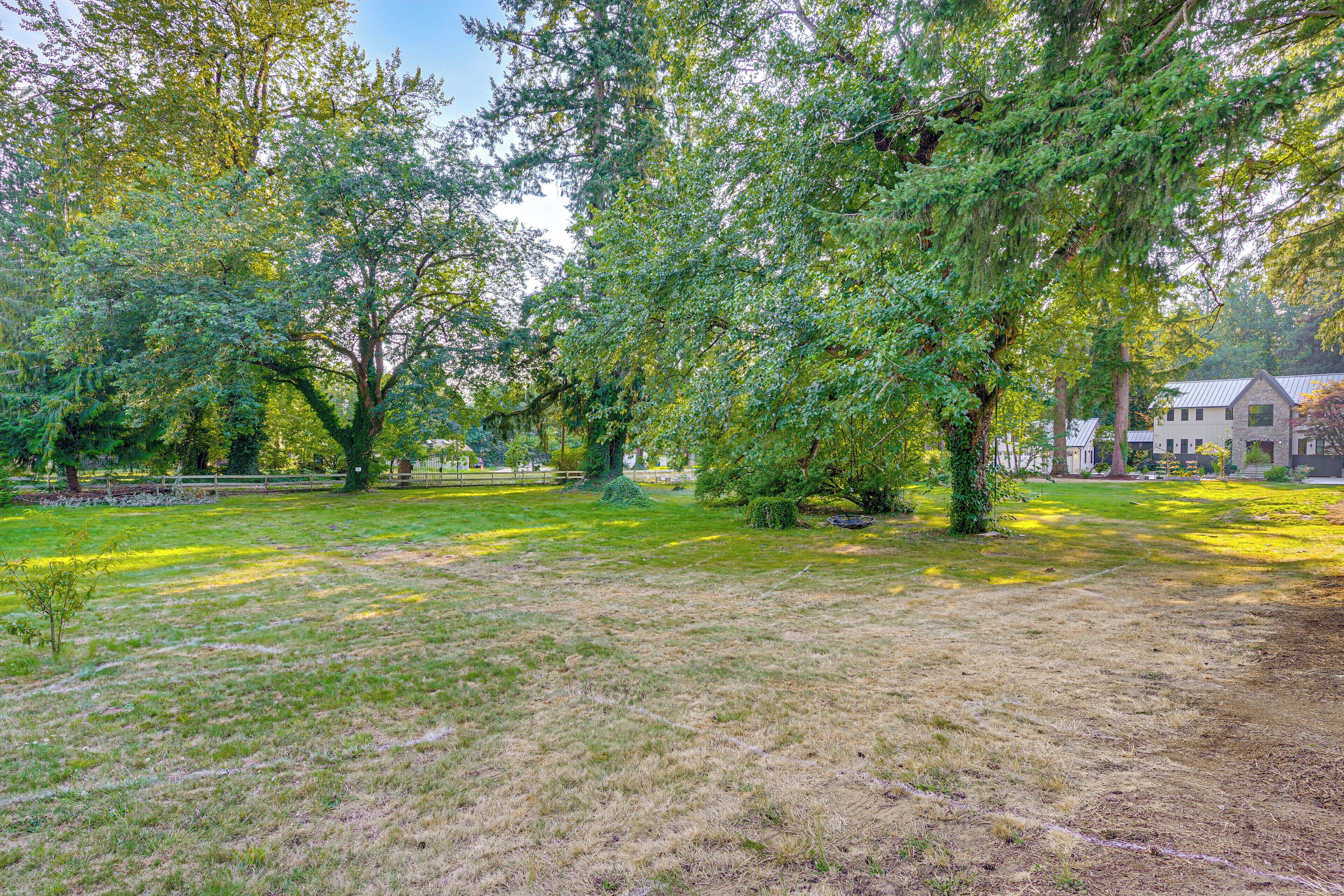 A park with mature trees, a grassy field, and a building with a stone facade in the background.