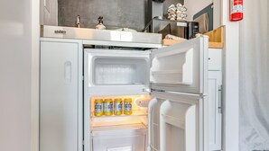 A white refrigerator with a freezer compartment and a shelf with four cans of Polar beer. - Waterbury Studio 12 Mi to Bolton Valley Ski Resort (Waterbury)