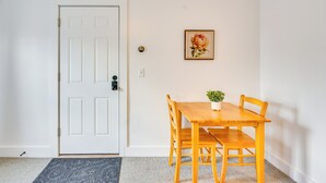 A dining area with a wooden table and chairs, a white door, and a framed picture on the wall. - Waterbury Studio 12 Mi to Bolton Valley Ski Resort (Waterbury)