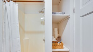 Ein Badezimmer mit Dusche, Handtuchhalter und Ablage für Toilettenartikel.