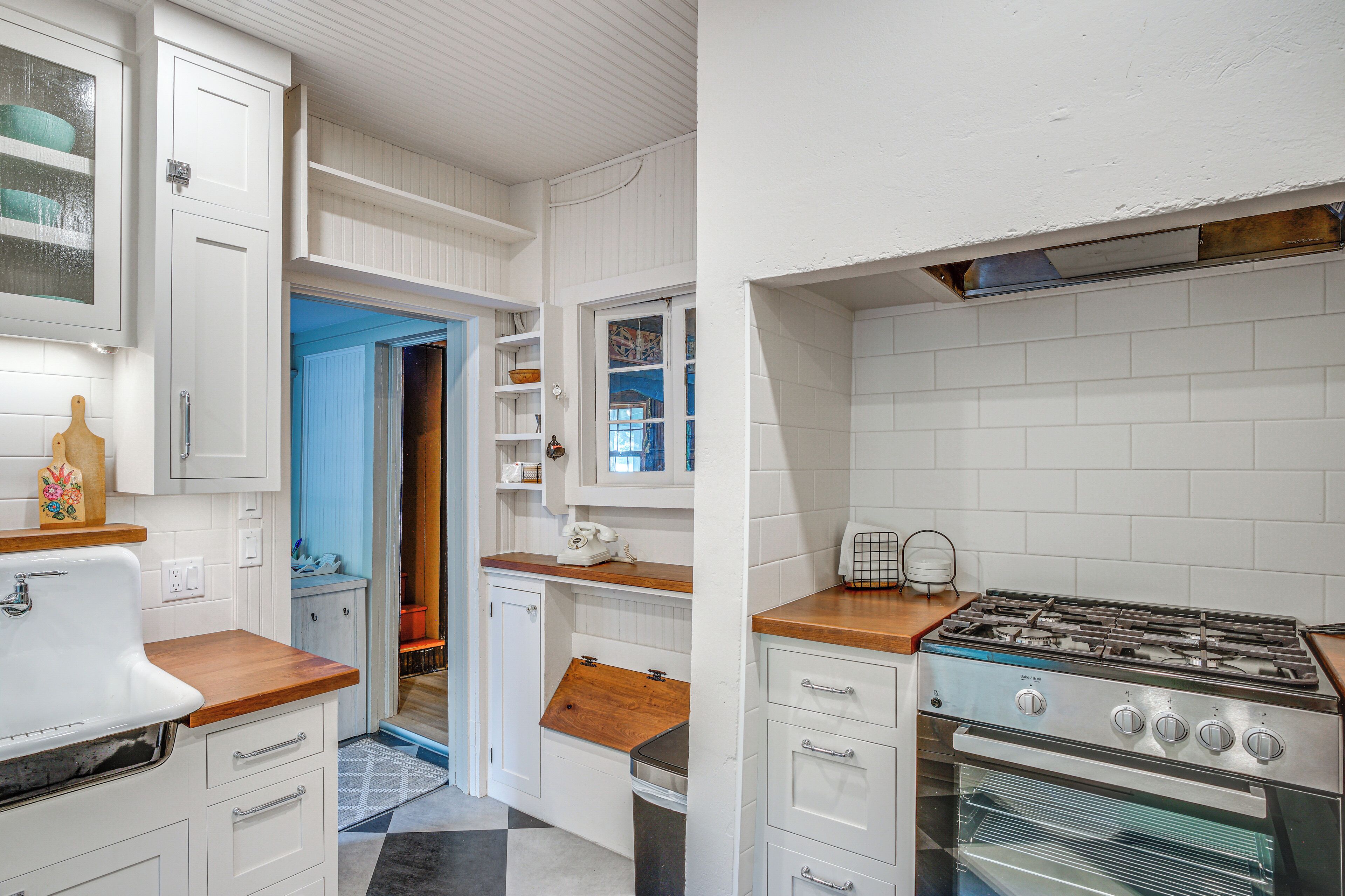 Una cocina con muebles blancos, encimera de madera, estufa a gas y horno empotrado.