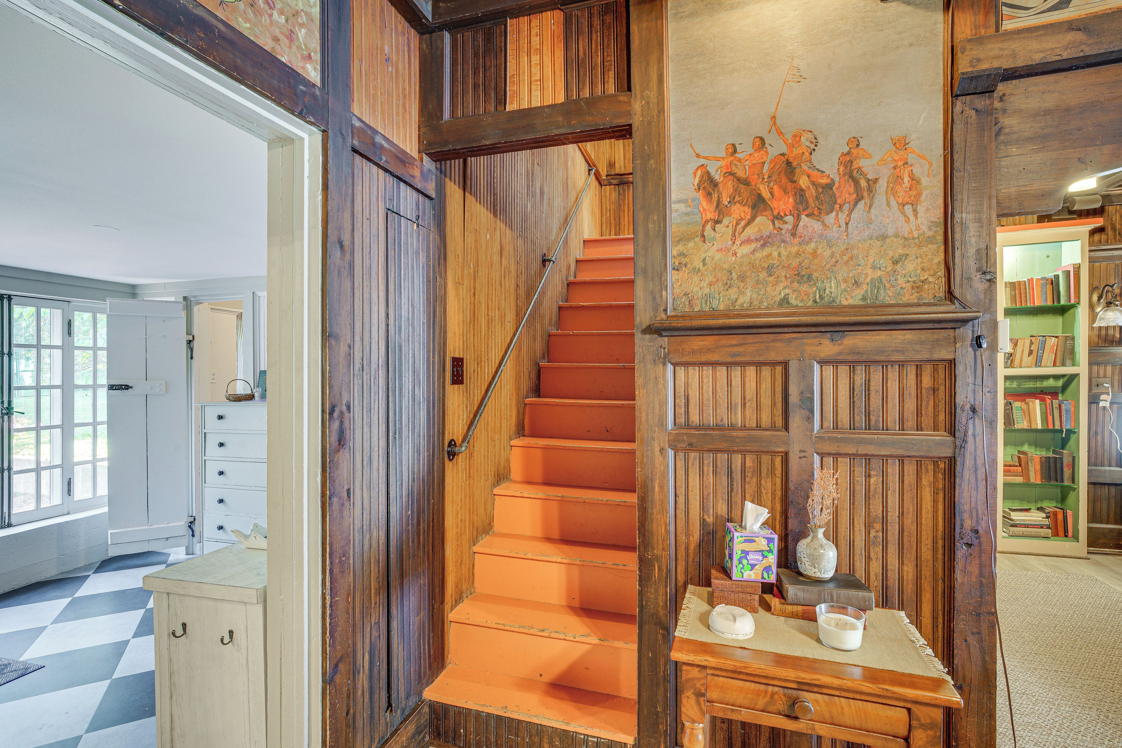 Un escalier en bois orné d’une fresque murale, une bibliothèque et un sol à carreaux.