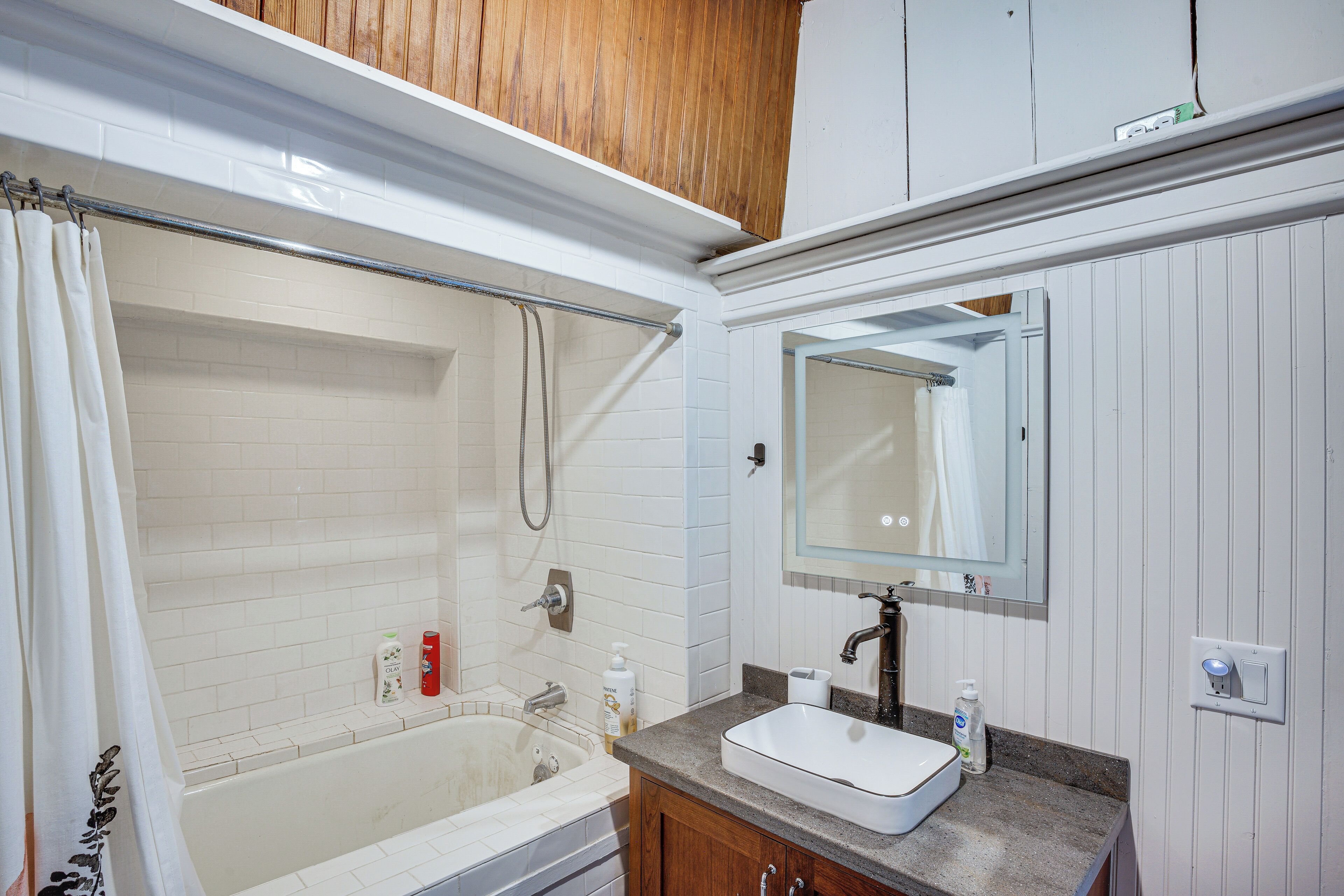 A bathroom with a bathtub, shower, sink, and mirror.