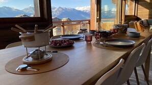 A dining table set with dishes, glasses, and a pot, overlooking a mountain view. - Grimpeur 9 ski in/out, Spa Access (Haute-Nendaz)