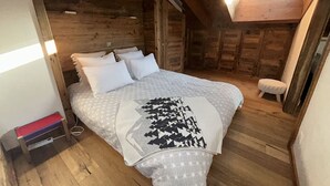 A wooden cabin bedroom with a bed, pillows, and a bench. - Grimpeur 9 ski in/out, Spa Access (Haute-Nendaz)