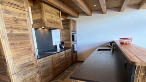 A kitchen with wooden cabinets, a stone floor, and a black countertop. - Grimpeur 9 ski in/out, Spa Access (Haute-Nendaz)