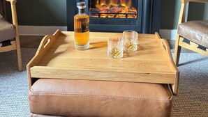 A cozy living room with a fireplace, a wooden coffee table with a bottle and glasses, leather chairs, and a bookshelf. - Modern, Stylish Flat on Baker Street — 5 mins walk to Stirling Castle (Stirling)